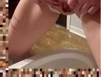Petite tattooed girl pees into toilet while standing up