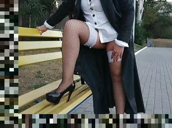 Slut walking in the park in a raincoat and black fishnet stockings with a white elastic band