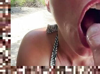 A milf gives a blow job to a mystery man on the beach. He comes on her face and in her mouth.